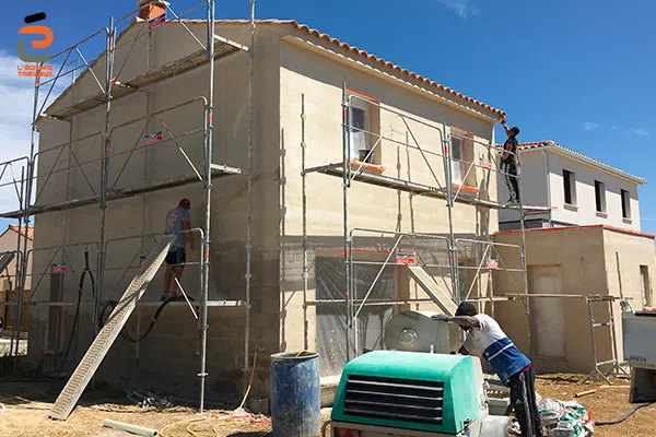Artisan façadiers de l'Équipe Travaux en train d'appliquer un enduit monocouche sur les façades d'une villa neuve
