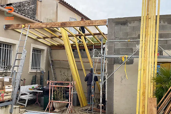 Artisan charpentier de l'Équipe Travaux en train de poser une charpente bois pour l'extention d'une maison