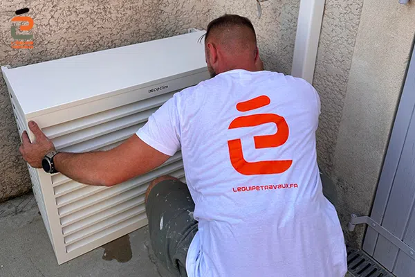 Artisan climatitien de l'Équipe Travaux en train de poser une unité externe de climatisation et son coffre d'abillage en métal