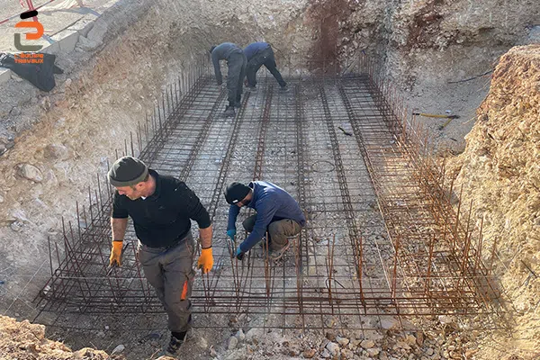 Artisans maçons de l'Équipe Travaux en train de mettre en place le ferraillage d'une piscine en béton armé